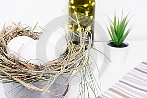 Easter white chicken eggs in straw nest, green spring plants and easter holiday decoration on white background and country style