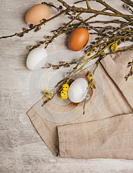 Easter white egg with little yellow chick toys in nest on a grey table, in rustic style