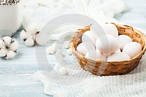 Easter white eggs in a wicker basket on a light background Background for a postcard