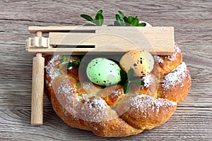 Easter wooden rattle - clapper - ratchet with eggs and sweet braided bread, homemade on wooden background
