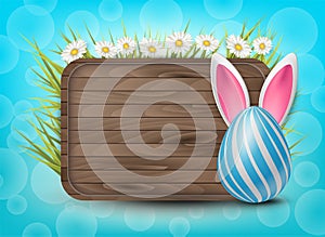 Easter wooden sign with painted 3d realistic eggs with bunny ears in green glass and flowers on bright blue bokeh backdrop.