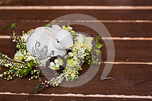 Easter wreath with bunny, flowers and eggs on a wooden background.