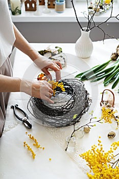 Easter wreath diy with woman hands, flowers on table, handicraft