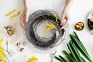 Easter wreath diy with woman hands, flowers on table, handicraft