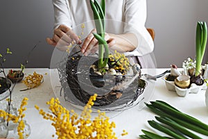 Easter wreath diy with woman hands, flowers on table, handicraft