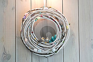 Easter wreath made of twigs eggs and birds on wooden wall background