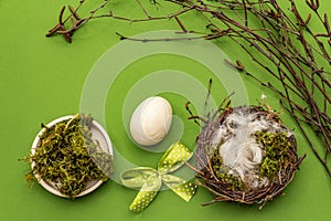 Easter zero waste decor, DIY concept. Design element and decor. Bird nest, egg, moss, birch branches, feather. Green background