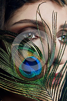 Eastern Arab woman with a peacock feather in her hands near her face. Beauty fashion makeup Arab women, big beautiful eyes.