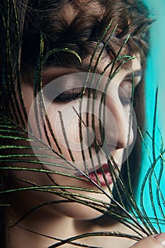 Eastern Arab woman with a peacock feather in her hands near her face. Beauty fashion makeup Arab women, big beautiful eyes.