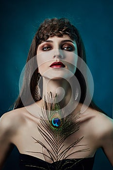 Eastern Arab woman with a peacock feather in her hands near her face. Beauty fashion makeup Arab women, big beautiful eyes.