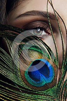 Eastern Arab woman with a peacock feather in her hands near her face. Beauty fashion makeup Arab women, big beautiful eyes.