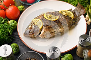 Eastern or European cuisine, Fried fish with fresh vegetables, on a wooden black background. I also eat healthy food. Seafood,