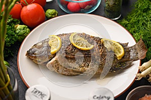 Eastern or European cuisine, Fried fish with fresh vegetables, on a wooden black background. I also eat healthy food. Seafood,