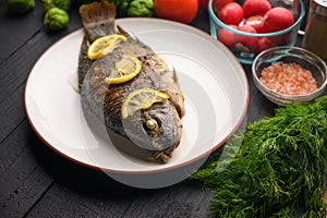 Eastern or European cuisine, Fried fish with fresh vegetables, on a wooden black background. I also eat healthy food. Seafood,