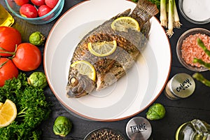 Eastern or European cuisine, Fried fish with fresh vegetables, on a wooden black background. I also eat healthy food. Seafood,
