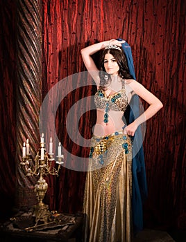 Eastern princess with crown. Attractive, sensual woman in luxury palace