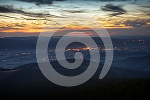 Eastern Sudetes, a mountain landscape after sunset with the illuminated city of Bystrzyca Klodzka in a mountain valley.