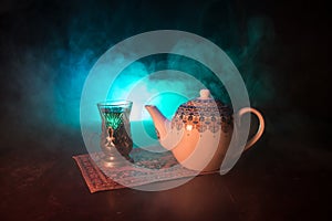 Eastern tea in traditional glasse and pot on black background with lights and smoke. Eastern tea concept. Armudu traditional Azerb
