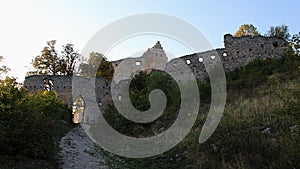 Eastern walls and main entrance to ruins of early gothic castle Topolcany during early fall sunset.