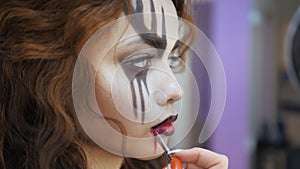 Easy Halloween Makeup. Applying makeup to the face. Applying red paint on the lips