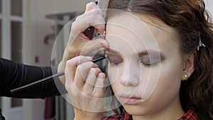 Easy Halloween Makeup. Girl in a beauty salon. Applying a stylistic pattern on the face of the model. The work of a master stylist