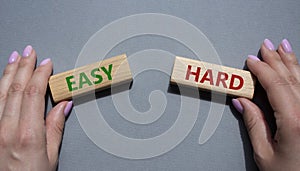 Easy or Hard symbol. Concept word Easy or Hard on wooden blocks. Businessman hand. Beautiful grey background. Business and Easy or