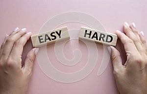 Easy or Hard symbol. Concept word Easy or Hard on wooden blocks. Businessman hand. Beautiful pink background. Business and Easy or