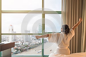 Easy lifestyle Asian woman waking up from good sleep in weekend morning taking some rest, relaxing in comfort bedroom at hotel