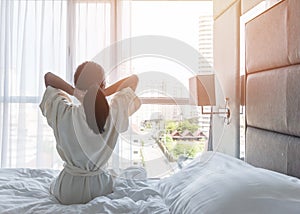 Easy lifestyle Asian woman waking up from good sleep in weekend morning taking some rest, relaxing in comfort bedroom at hotel