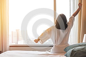 Easy lifestyle Asian woman waking up from good sleep in weekend morning taking some rest, relaxing in comfort bedroom at hotel