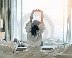 Easy lifestyle Asian woman waking up from good sleep in weekend morning taking some rest, relaxing in comfort bedroom at hotel