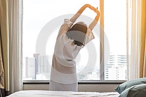 Easy lifestyle Asian woman waking up in weekend morning taking some rest relaxing in comfort city hotel room