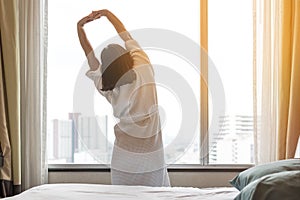 Easy lifestyle Asian woman waking up in weekend morning taking some rest relaxing in comfort city hotel room enjoying world lazy d
