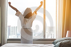 Easy lifestyle Asian woman waking up in weekend morning taking some rest relaxing in comfort city hotel room enjoying world lazy