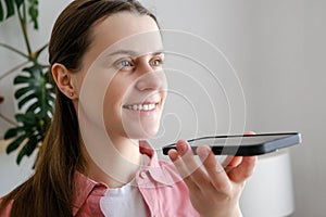 Easy mobile ai technology concept. Close up of smiling young woman holding phone speak activate virtual digital voice assistant on