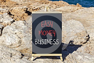 Easy money business symbol. Concept words Easy money business on beautiful black chalk blackboard. Beautiful red stone blue sea