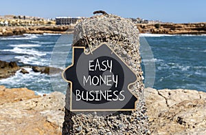 Easy money business symbol. Concept words Easy money business on beautiful black chalk blackboard. Beautiful red stone blue sea