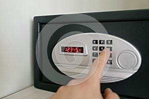 Easy password. Hand press key on black safety box in hotel room. Concept safe storage of money and documents