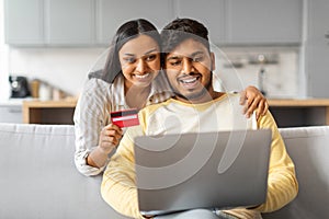 Easy Payments. Happy Indian Couple With Laptop And Credit Card At Home