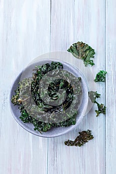 Easy three ingredient baked green kale chips with sea salt and olive oil, in gray bowl, vertical, top view