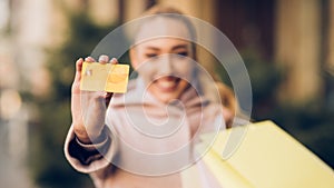 Easy to pay. Woman showing credit card, holding shopping bags