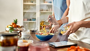 Eat the best. Close up of process of cooking. Couple preparing healthy meal in the kitchen, checking recipe using tablet