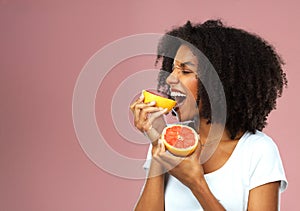 Eat grapefruit for the good of your health. Studio shot of an attractive young woman eating grapefruit against a pink