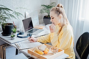 Eat Healthy While Working From Home. Healthy lunches work from home. Woman Freelancer eating Healthy Grain Snacks and