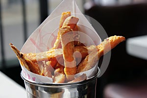 Freshly made sweet potato chips in a metal pot are ready to eat