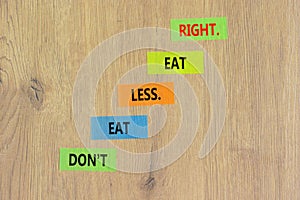 Eat less or right symbol. Concept words Do not eat less, eat right on colored paper. Beautiful wooden table wooden background.