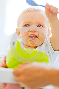 Eat smeared adorable baby playing with spoon