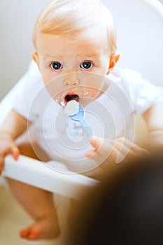 Eat smeared baby in chair feeding by mother photo