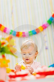 Eat smeared baby eating orange at birthday party