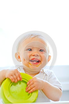 Eat smeared smiling baby girl playing with plate photo